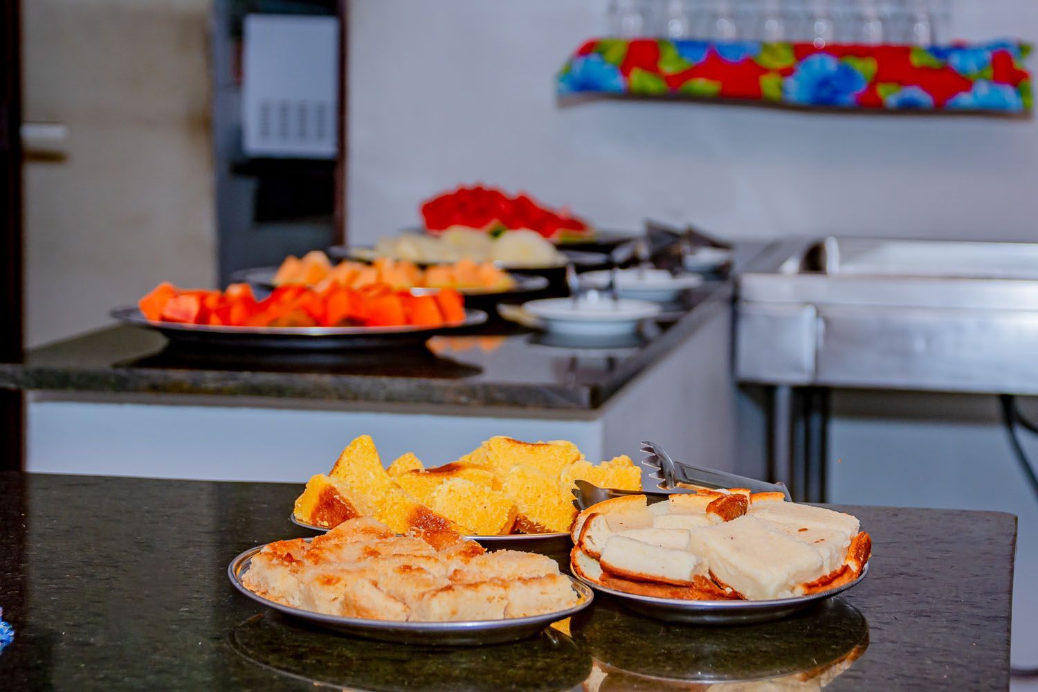 Uma mesa de bufê com pratos de comida e frutas.