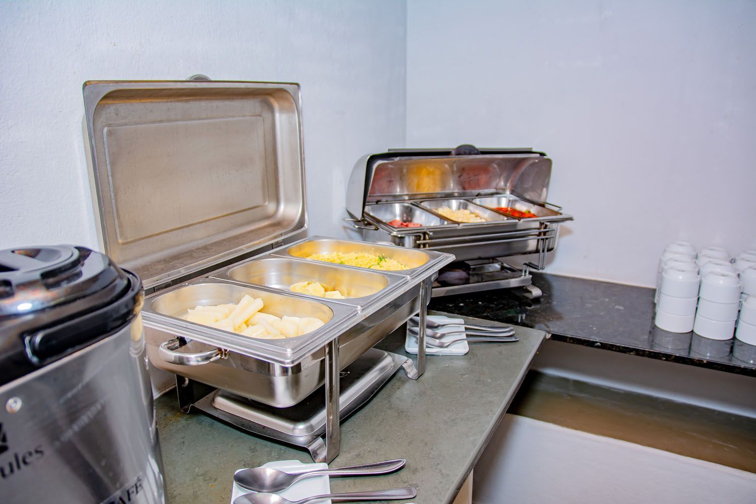 Uma mesa de buffet com um monte de bandejas de comida.