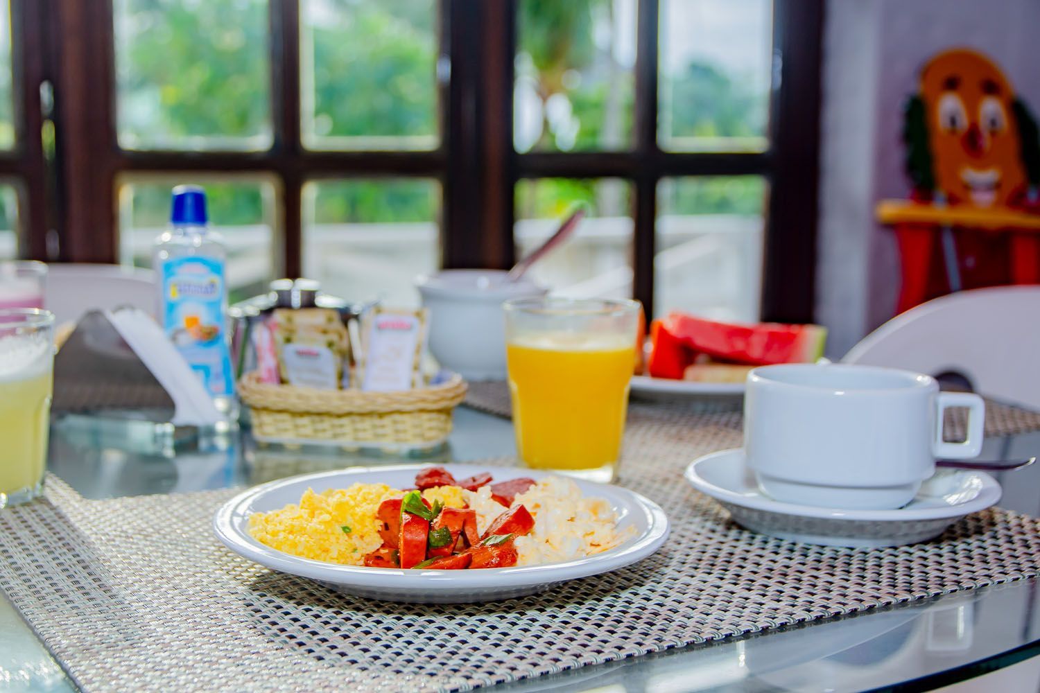 Há um prato de comida e um copo de suco de laranja sobre a mesa.