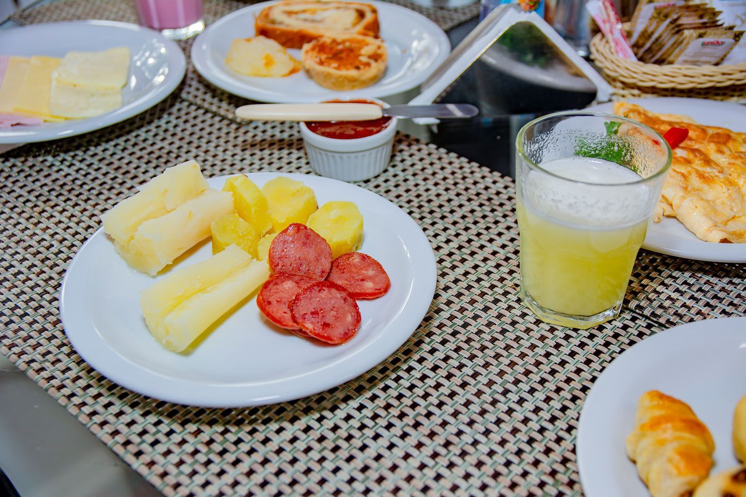 Uma mesa com pratos de comida e um copo de suco.