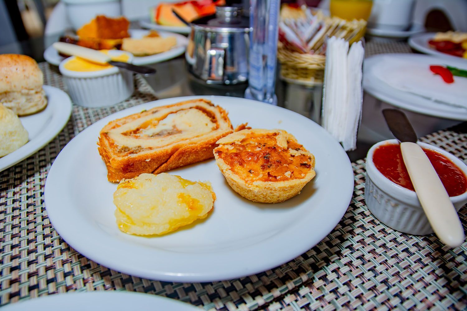 Um prato branco coberto com uma fatia de pão, um bolo e batatas sobre uma mesa.