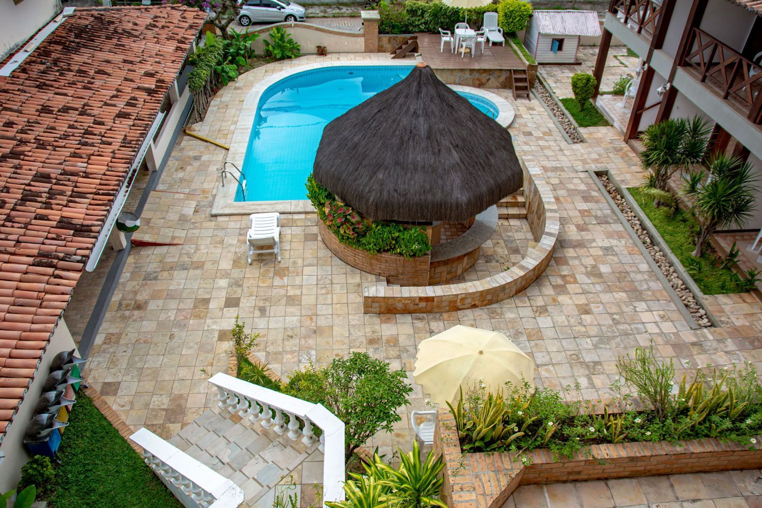 Uma vista aérea de uma piscina com uma cabana de palha no meio