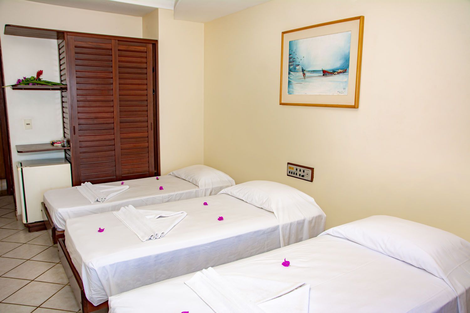 Um quarto de hotel com três camas e um quadro na parede.