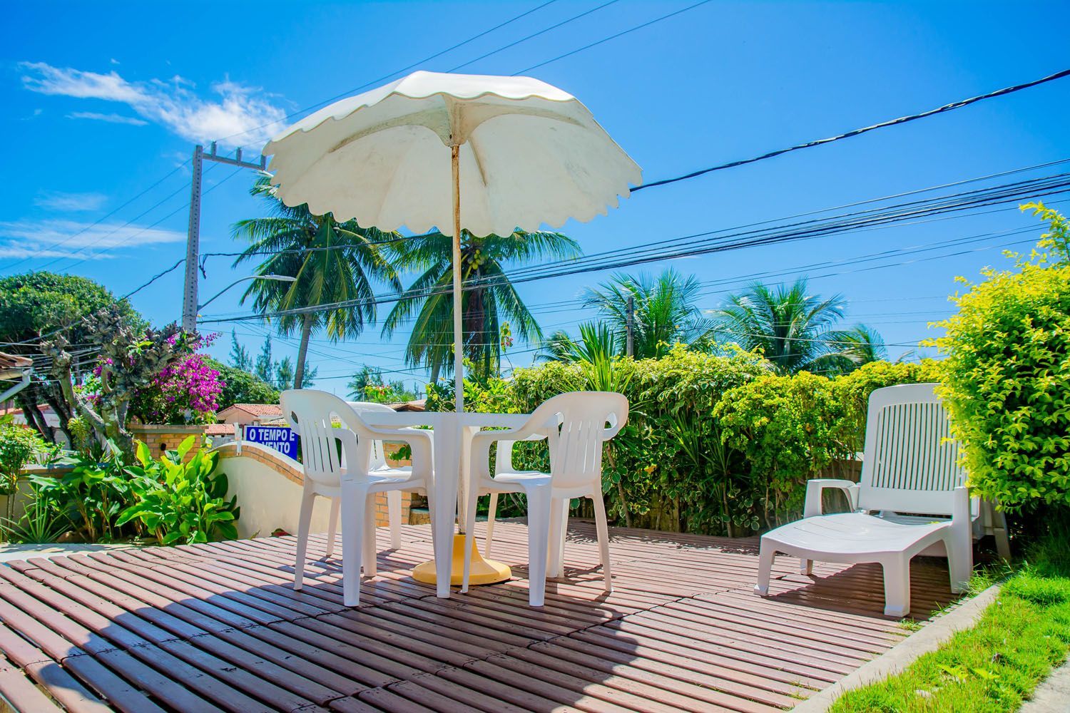 Um deck de madeira com mesa e cadeiras e guarda-sol.