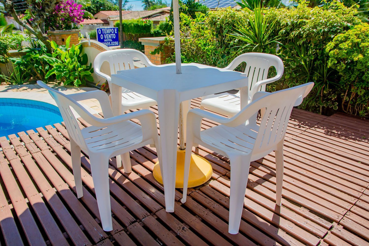 Uma mesa e cadeiras estão em um deck de madeira ao lado de uma piscina.