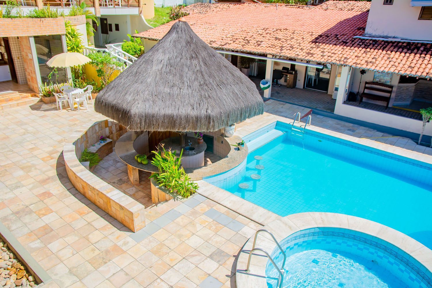 Uma vista aérea de uma grande piscina com uma cabana de palha no meio.