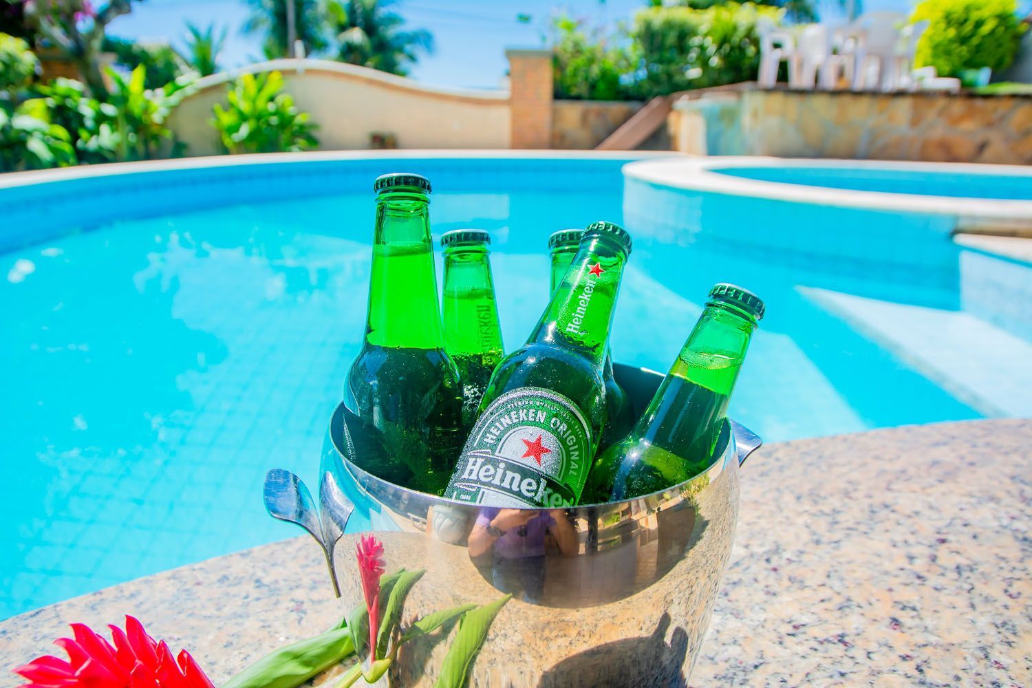 Um balde de cerveja está sobre uma mesa ao lado de uma piscina.