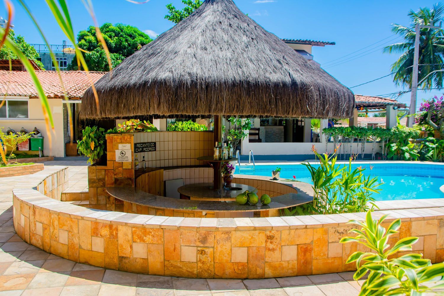 Uma cabana de palha fica ao lado de uma piscina.