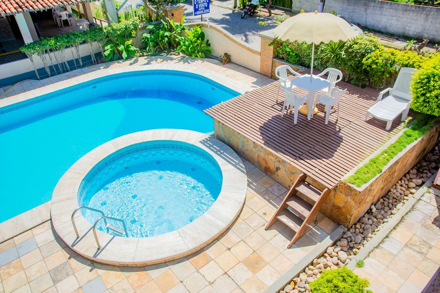 Uma vista aérea de uma grande piscina com banheira de hidromassagem, mesa e cadeiras.