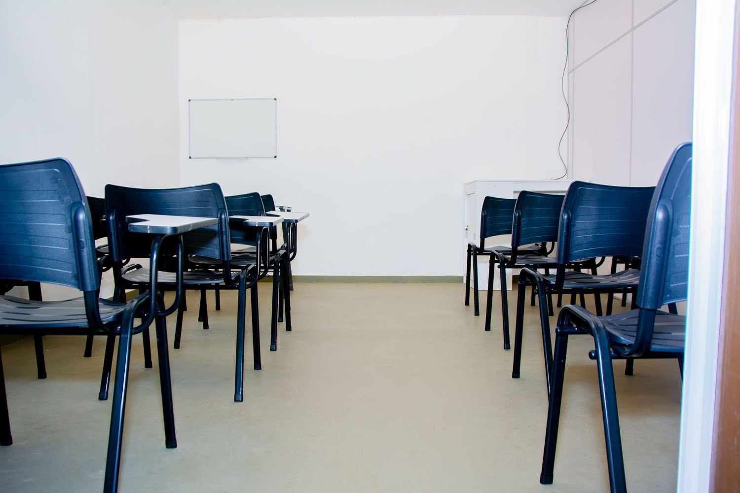 Uma sala de aula vazia com cadeiras e mesas azuis