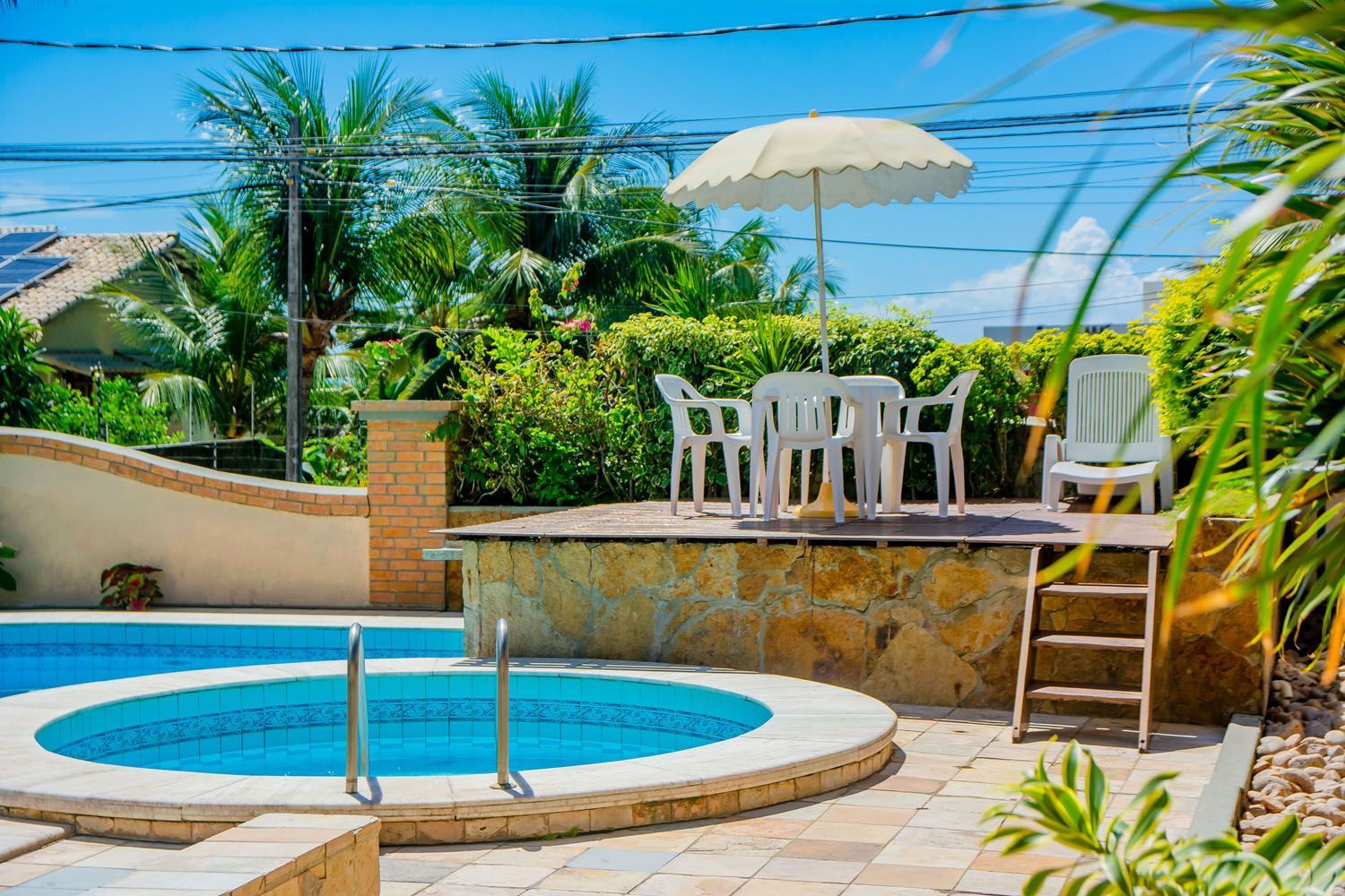 Uma piscina com mesa e cadeiras e guarda-sol.