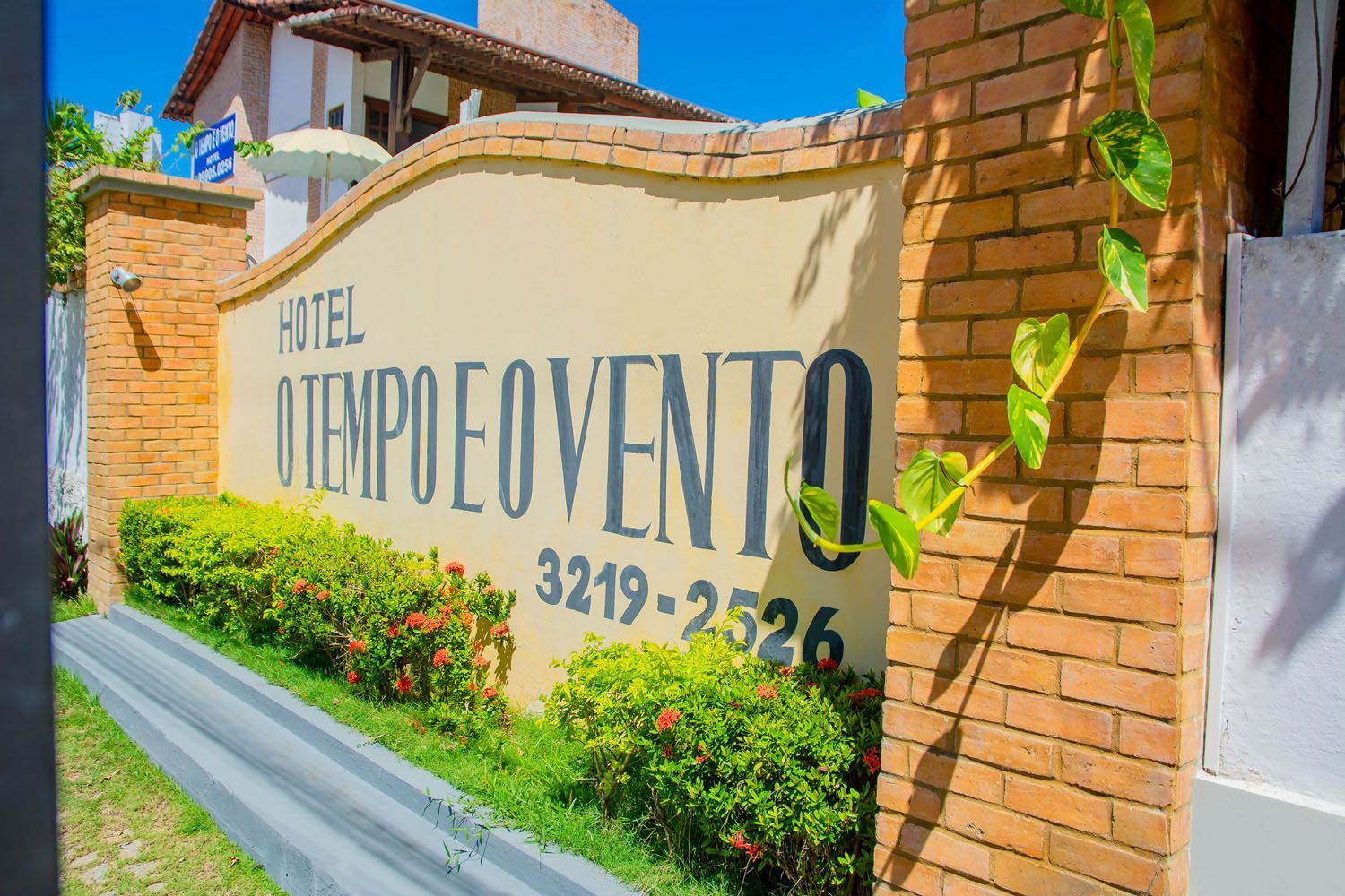 Uma parede de tijolos com uma placa que diz hotel o tempo e vento