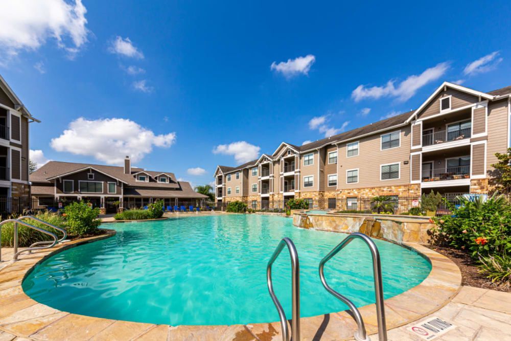 a large swimming pool in front of a large apartment building at Marquis at Katy in Katy, TX.