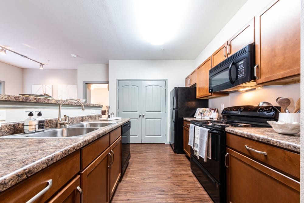 a kitchen with wooden cabinets, granite counter tops, stainless steel appliances, and a refrigerator at Marquis at Katy in Katy, TX.