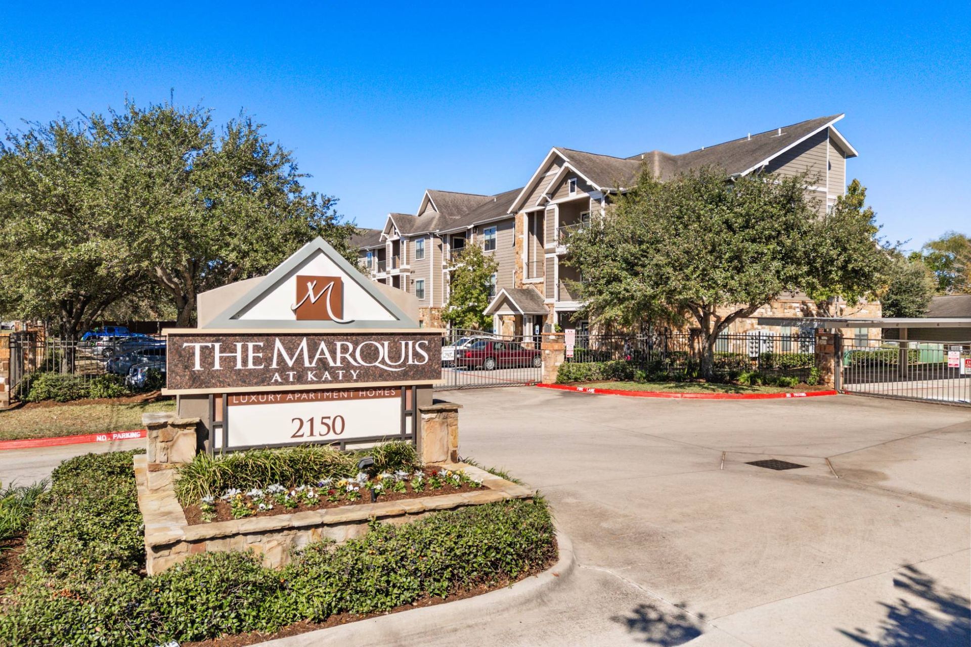 Gated entrance to The Marquis at Katy with stone sign and landscaping.