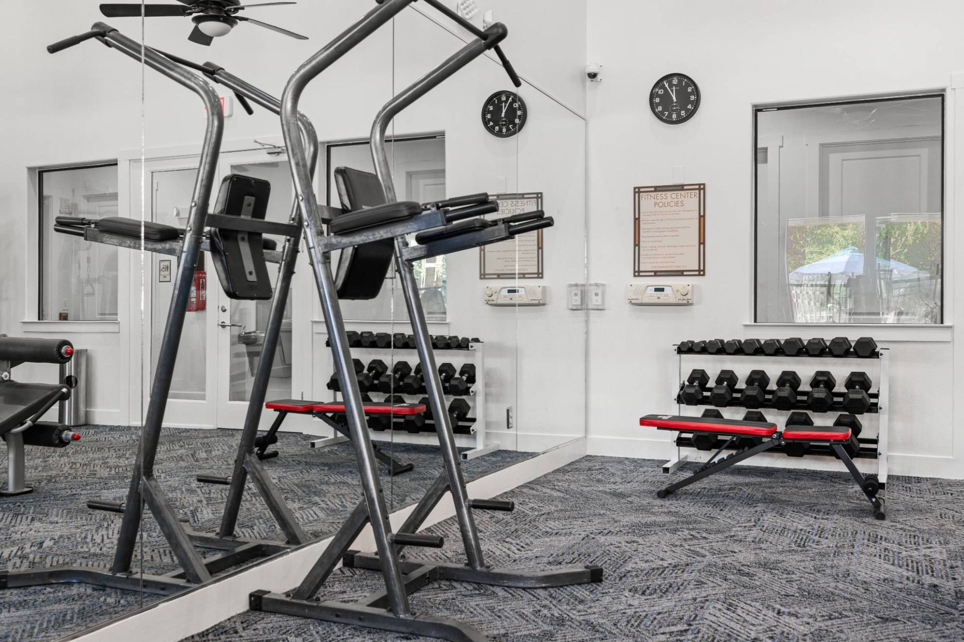 Residential gym with weight benches, dumbbells, and a mirrored wall.