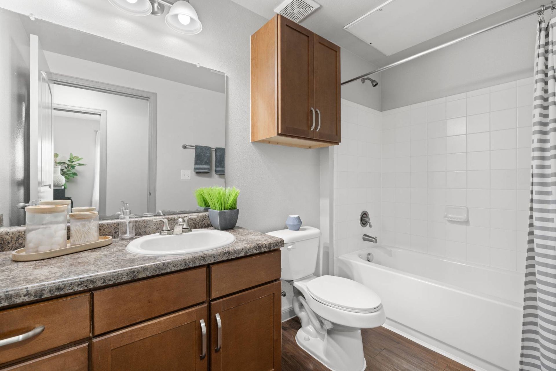Apartment bathroom with granite vanity, toilet, and tub/shower.