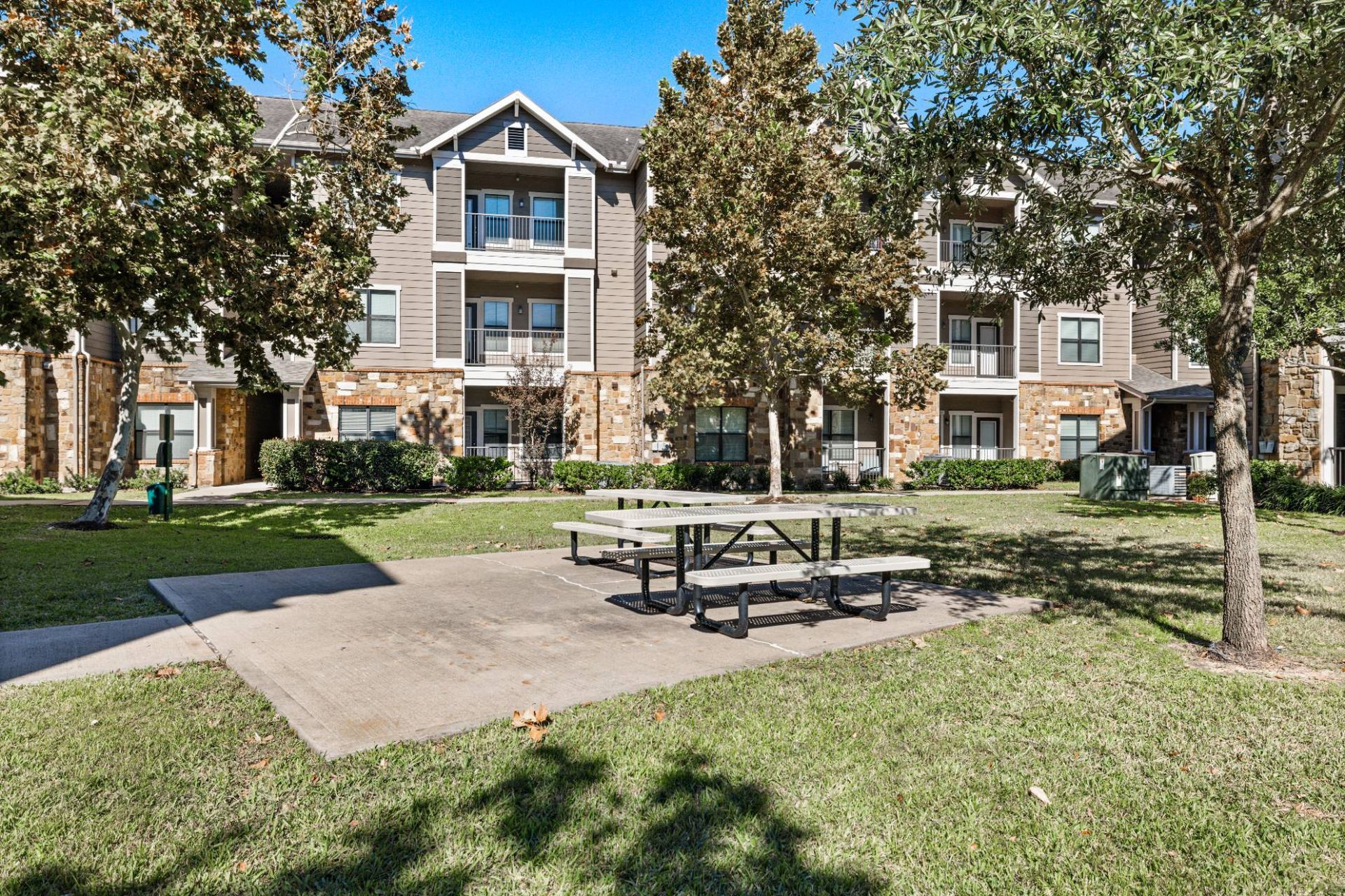 Exterior view of mid-rise apartment buildings with a grassy courtyard and picnic table.
