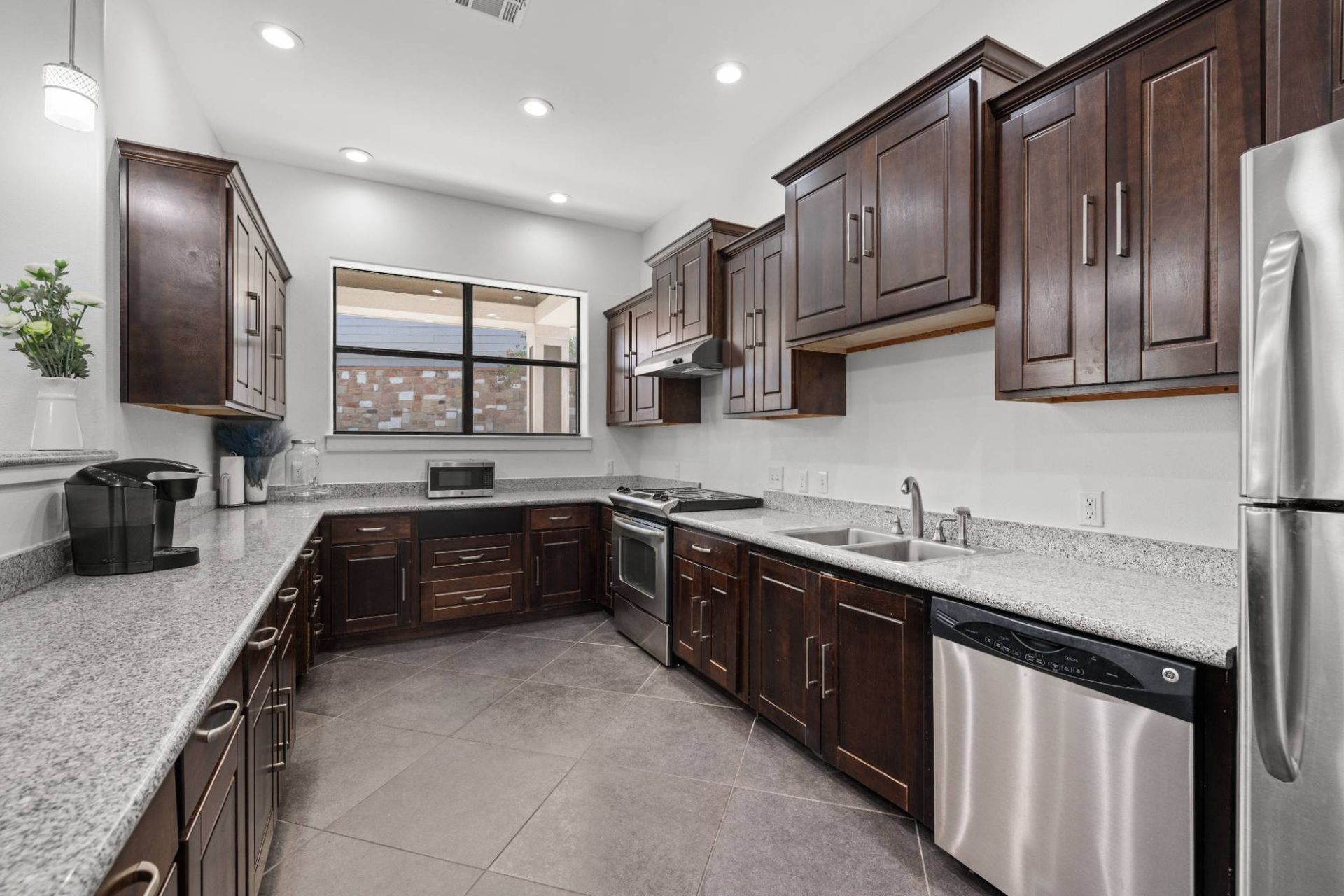 L-shaped kitchen with dark wood cabinets, granite countertops, and stainless steel appliances.