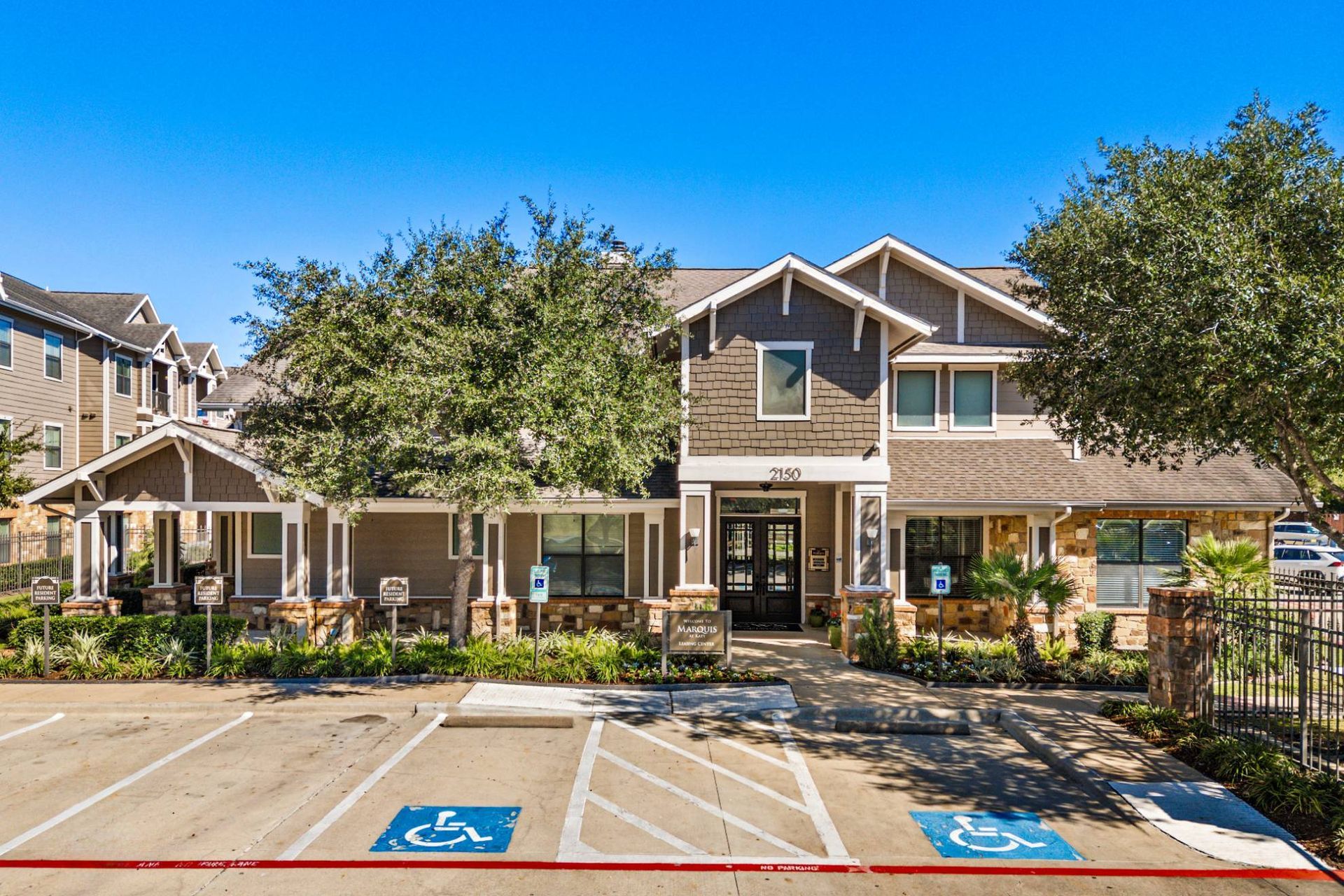 Exterior view of an apartment community with handicap parking, landscaping, and entry.