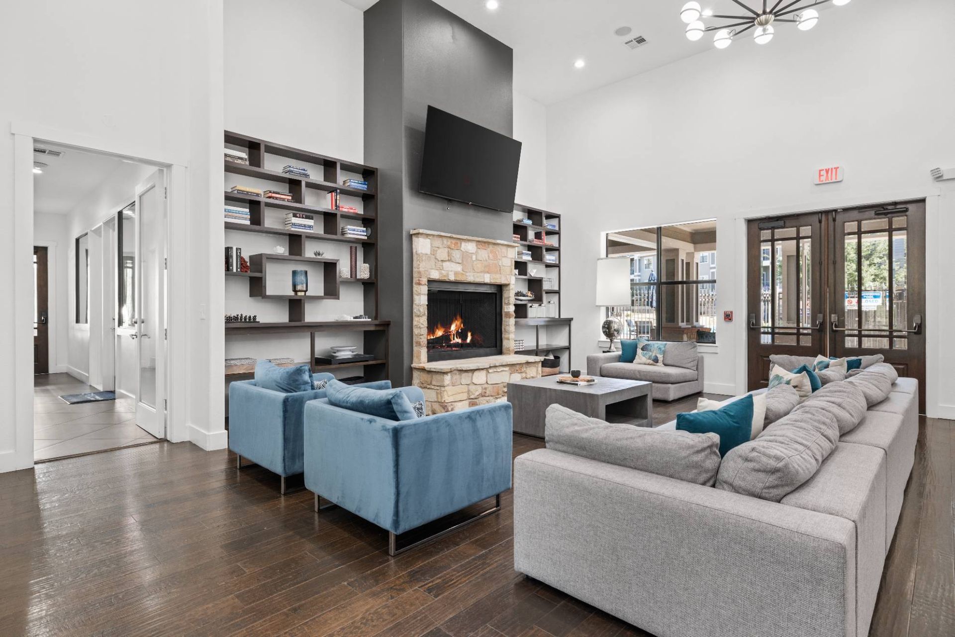 Interior community lounge with a stone fireplace, shelves, and seating.