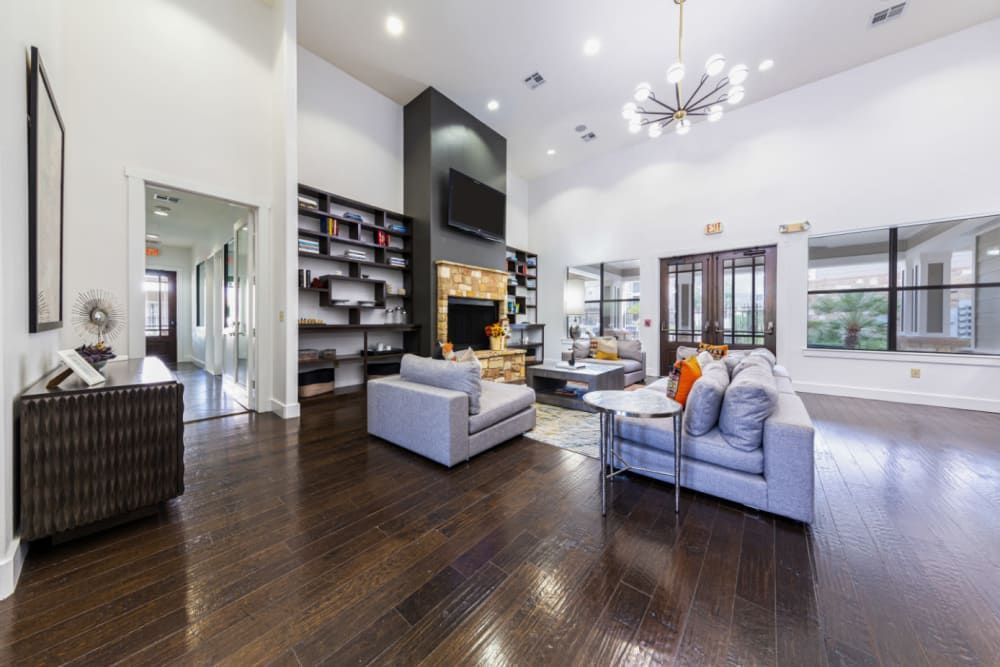 a clubhouse room with a couch, chair, table, and television at Marquis at Katy in Katy, TX.