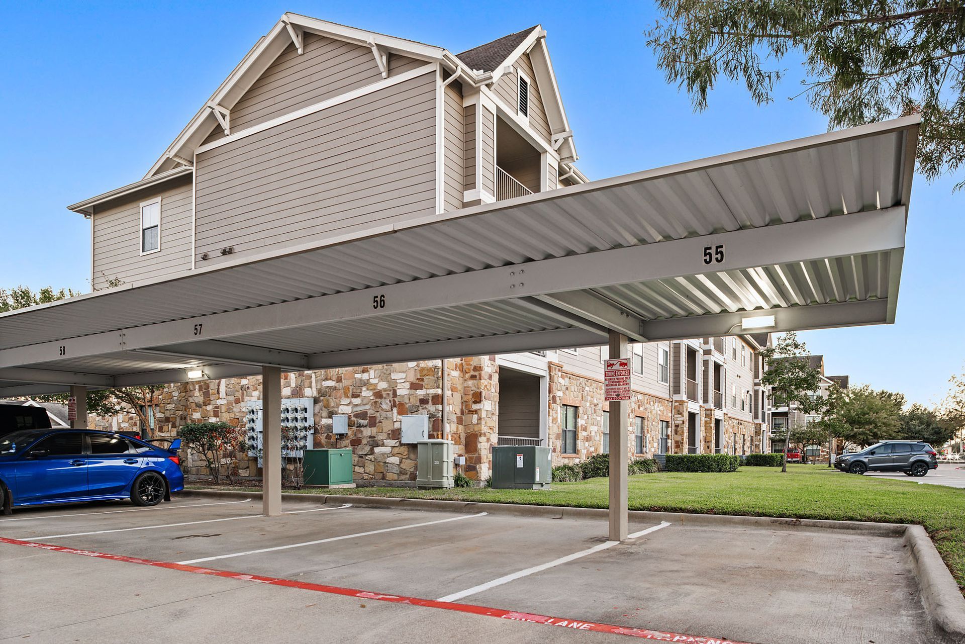 Covered parking area in front of multi-story apartment building. 