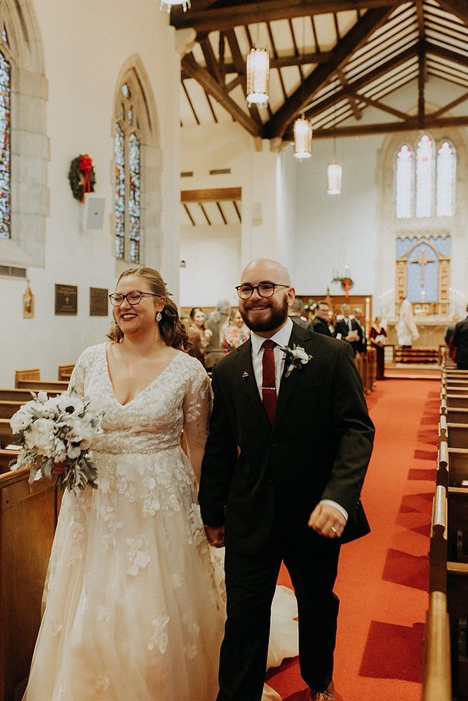 Newlyweds exiting a church. Bride in white dress with bouquet, groom in suit, smiling, walking down aisle.
