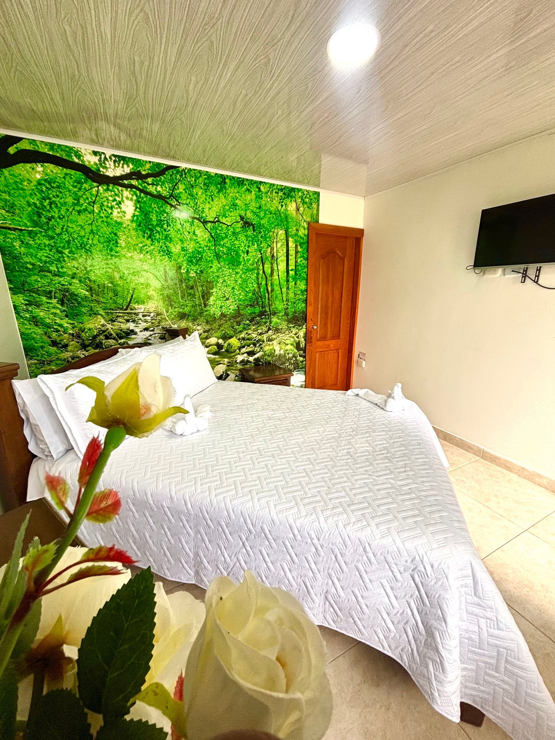 Habitación luminosa con cama blanca, mural de pared con temática de bosque verde, puerta de madera .