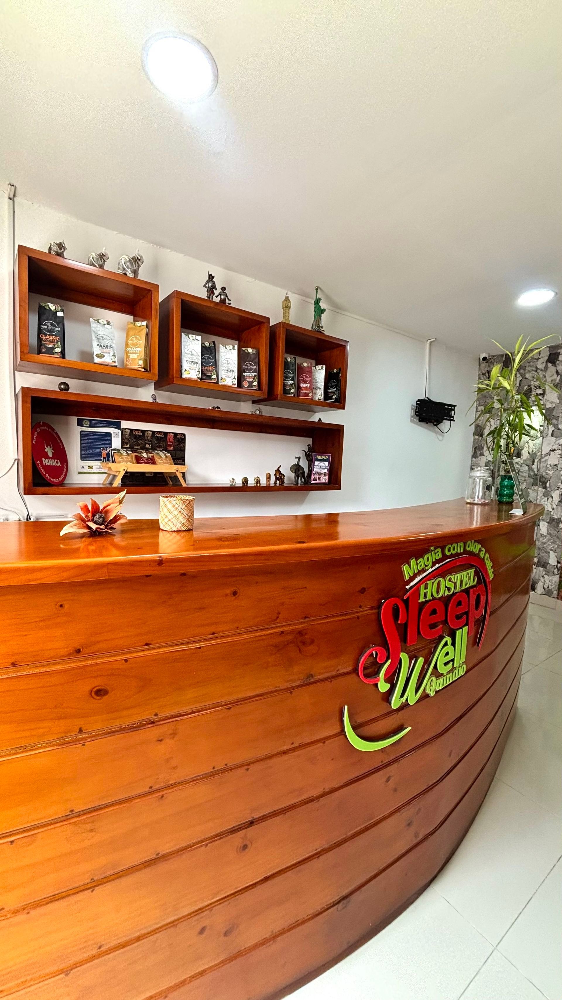 Mostrador de recepción revestido de madera en un vestíbulo luminoso con paredes blancas y estanterías empotradas detrás.