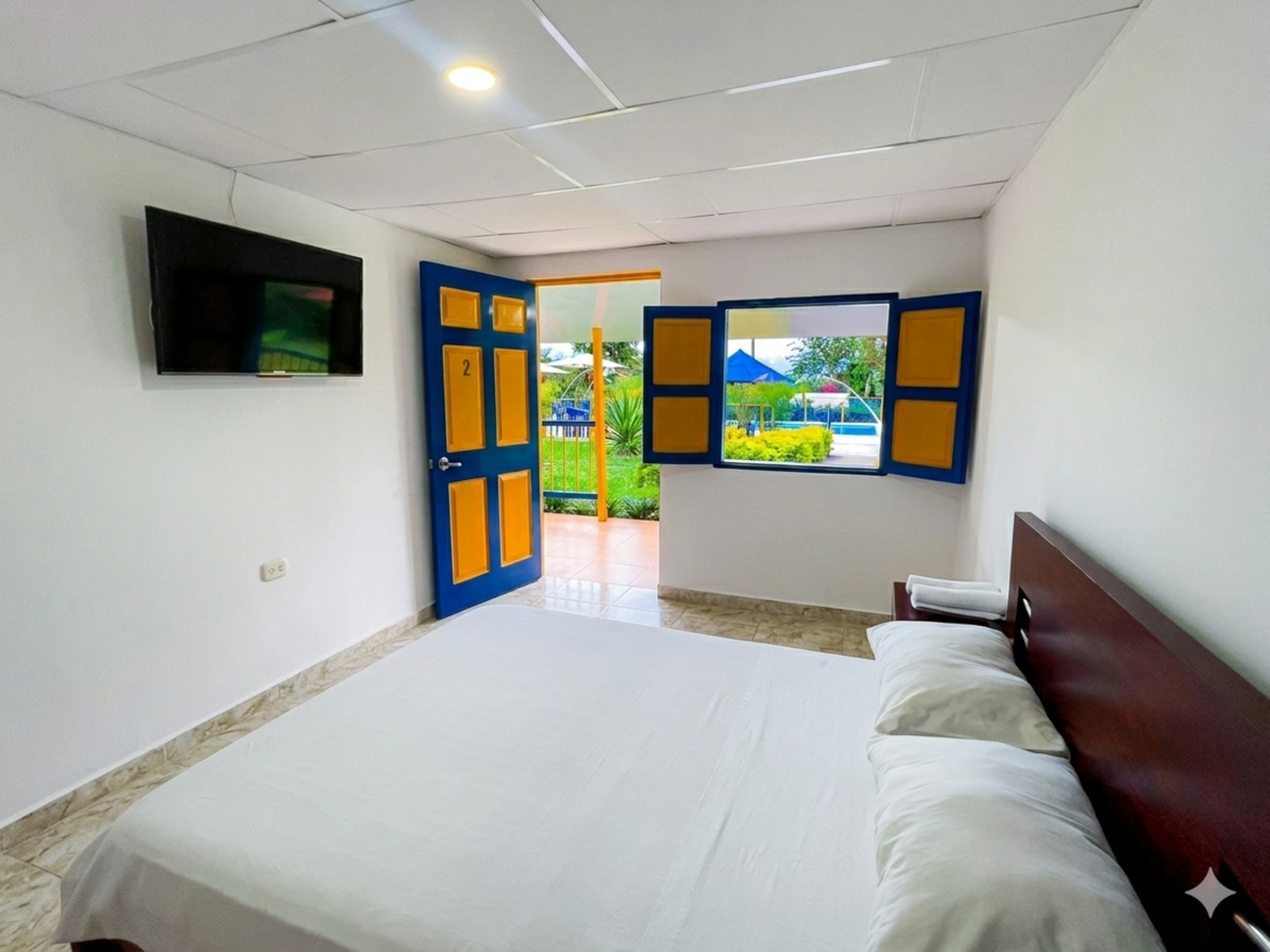 Habitación luminosa con cama, televisor montado en la pared