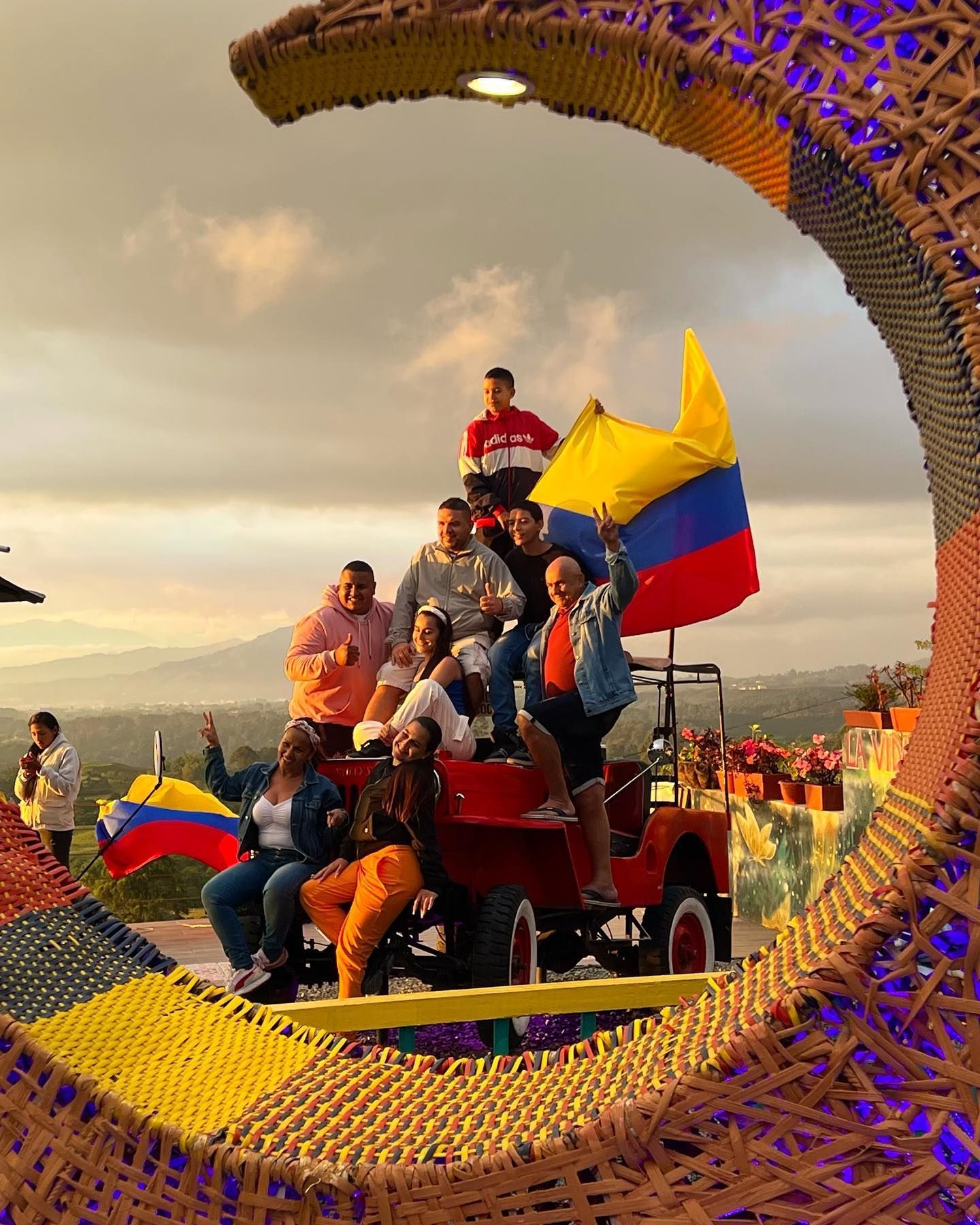 Personas que viajan en un vehículo rojo a través de un gigantesco anillo tejido, Mirador Encanto