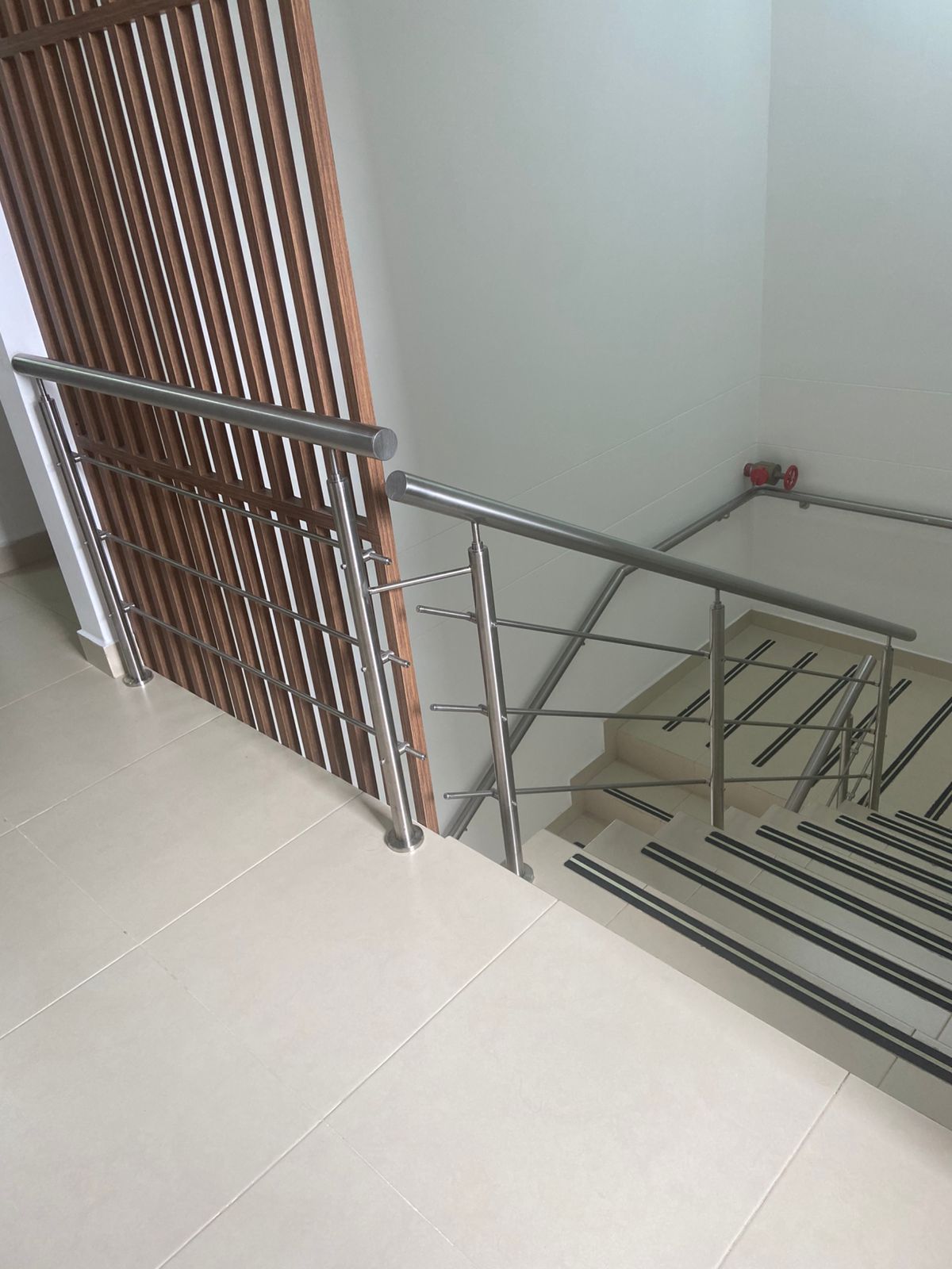 Escalera con barandilla metálica y pared de listones de madera. Suelos y escaleras de color claro.