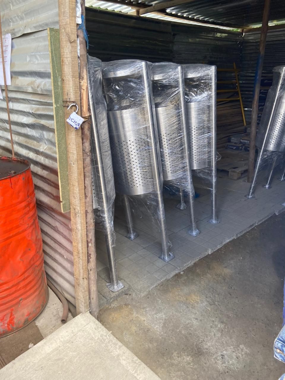 Varios tanques de acero inoxidable envueltos en plástico, dentro de una estructura de metal corrugado.