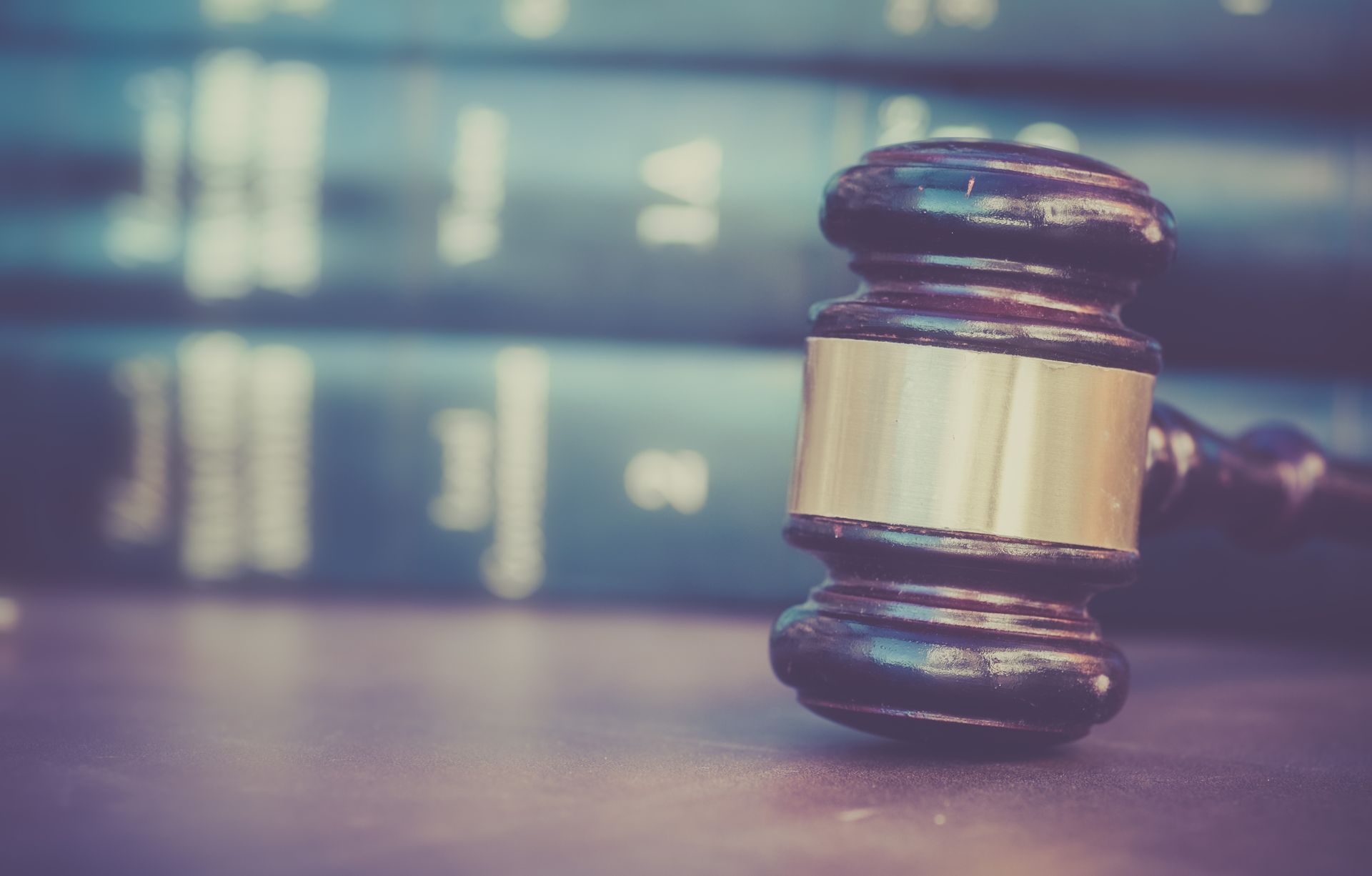 Gavel on a wooden surface with law books in the background, suggesting a courtroom or legal setting.