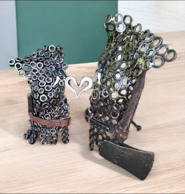 Metal sculpture of two figures, facing each other, with a heart shape between them.