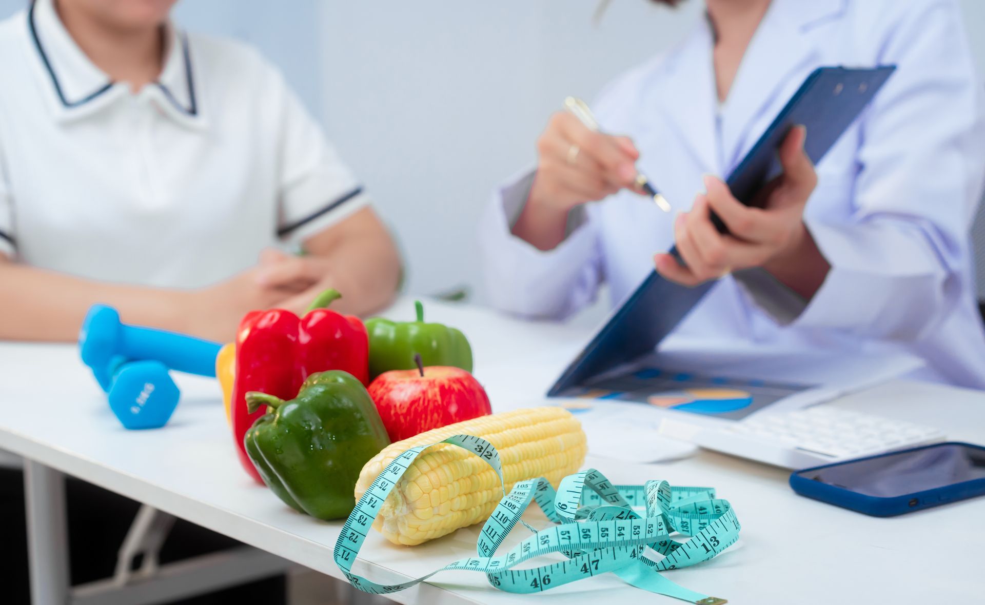 Dietitian consulting with a patient; vegetables, measuring tape, and weights on the table.