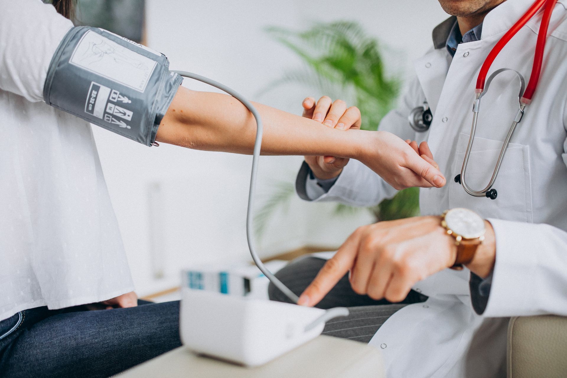 Doctor taking a patient's blood pressure with a cuff on the arm, indoors.