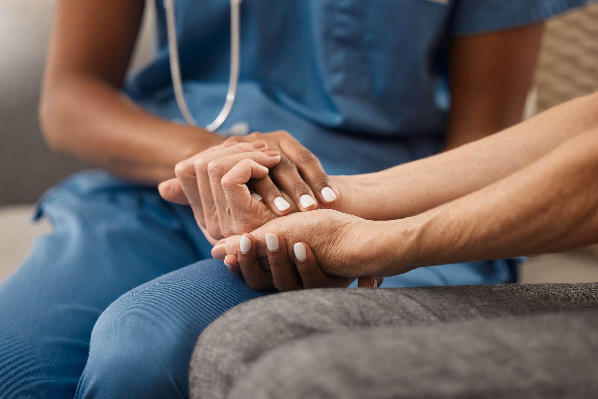 Nurse in blue scrubs holds patient's hands, offering comfort and support. Nurse in blue scrubs holds patient's hands, offering comfort and support.