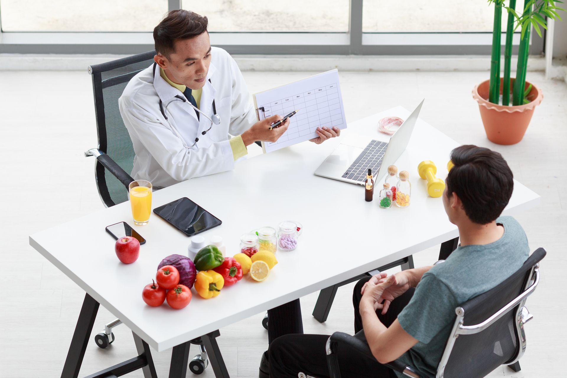 Doctor showing a chart to a patient at a desk, surrounded by fruits and juice. Doctor showing a chart to a patient at a desk, surrounded by fruits and juice.