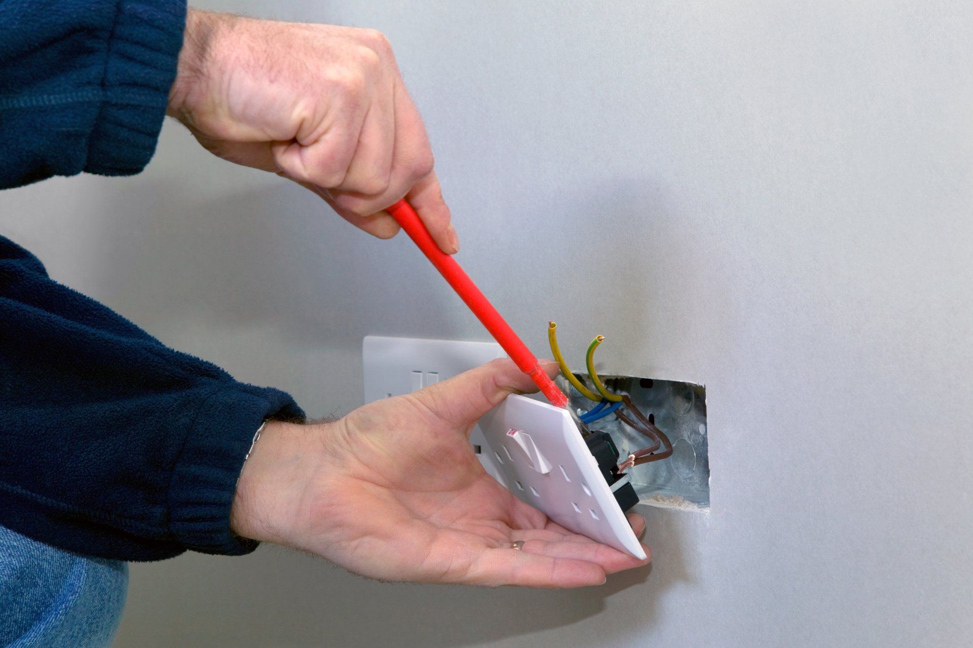 An electrician's hands carefully installing a power socket with focused precision.