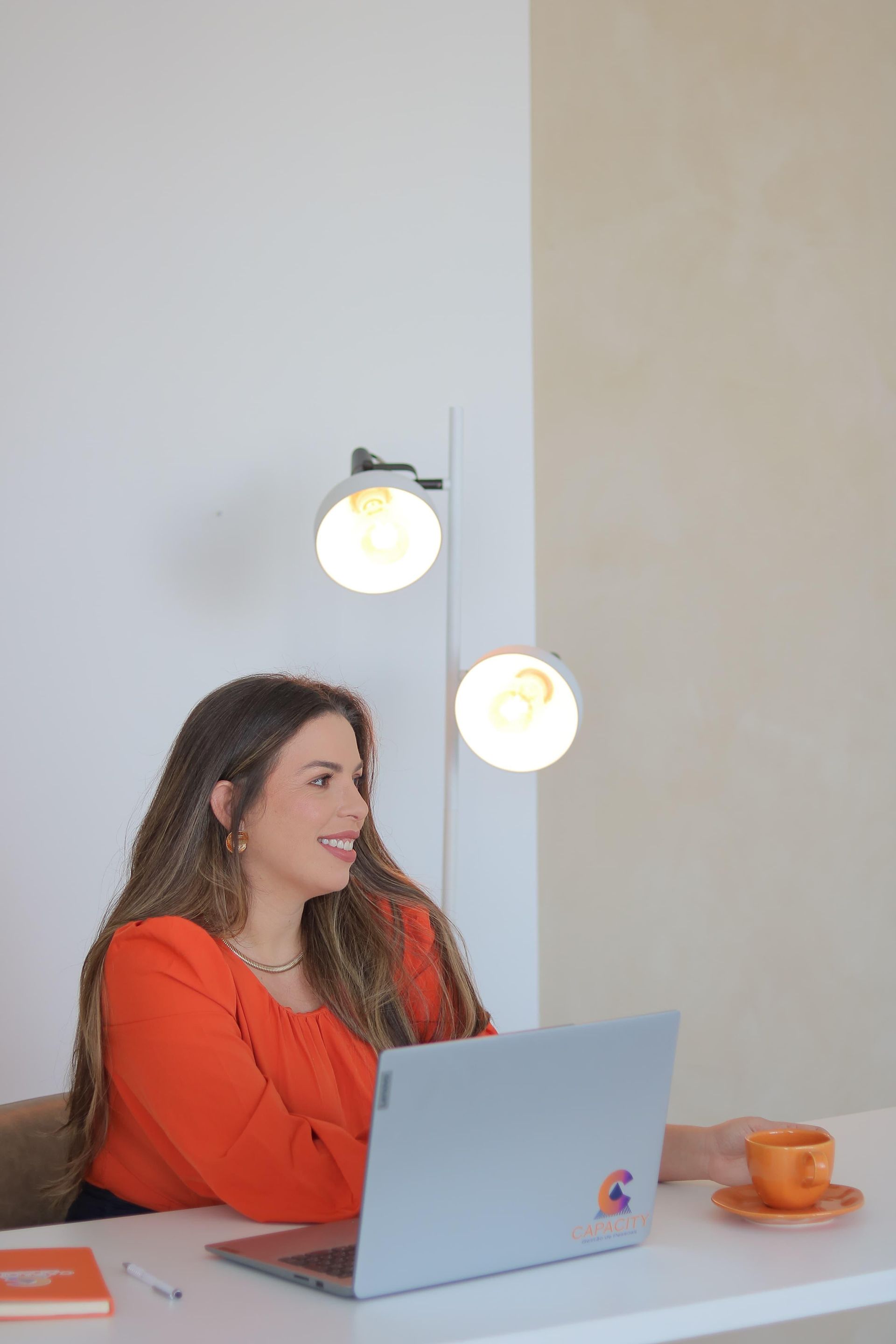 Uma mulher está sentada à mesa usando um laptop.