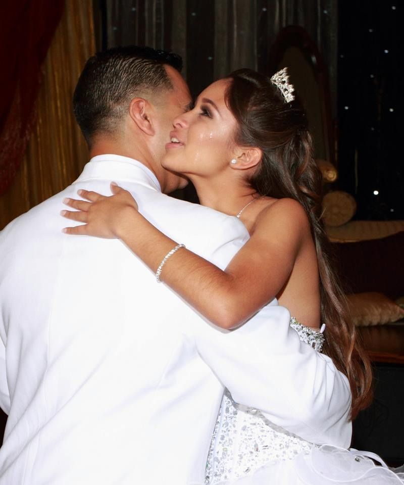 Couple in white formal wear embracing and gazing at each other at a celebration