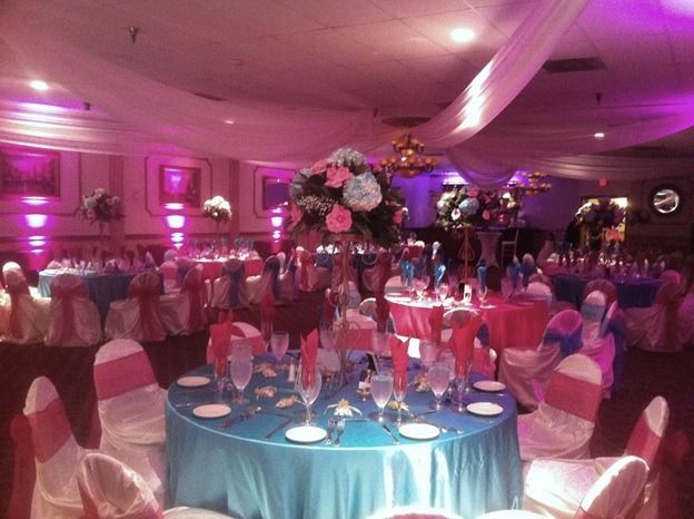 Elegant banquet hall with round tables, pink uplighting, and floral centerpieces set for an event