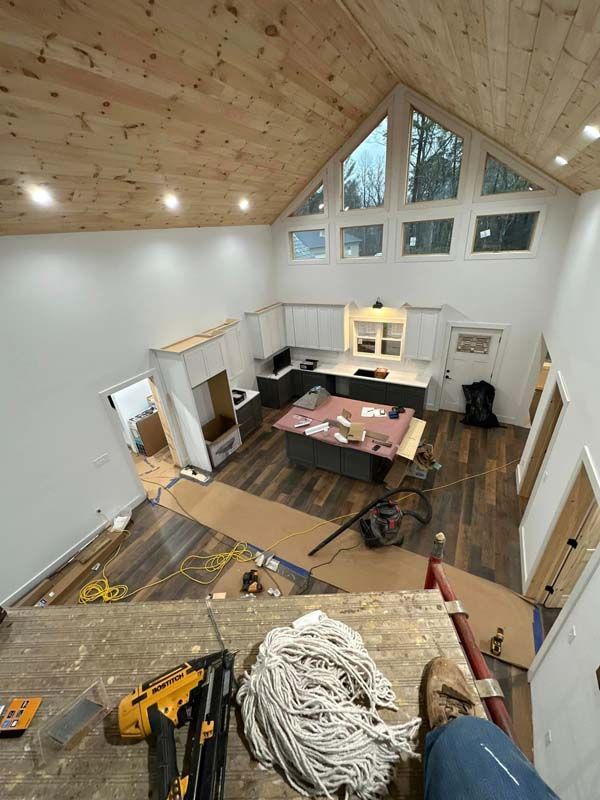 Interior construction view of a kitchen with unfinished cabinets, wood ceiling, and exposed flooring.
