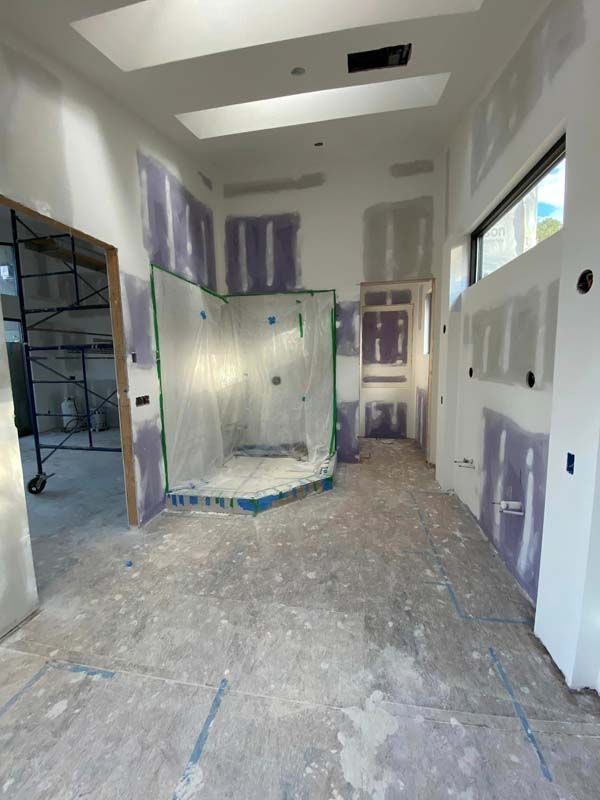 Interior construction: Unfinished bathroom with drywall, covered shower, unfinished floor, and natural light.