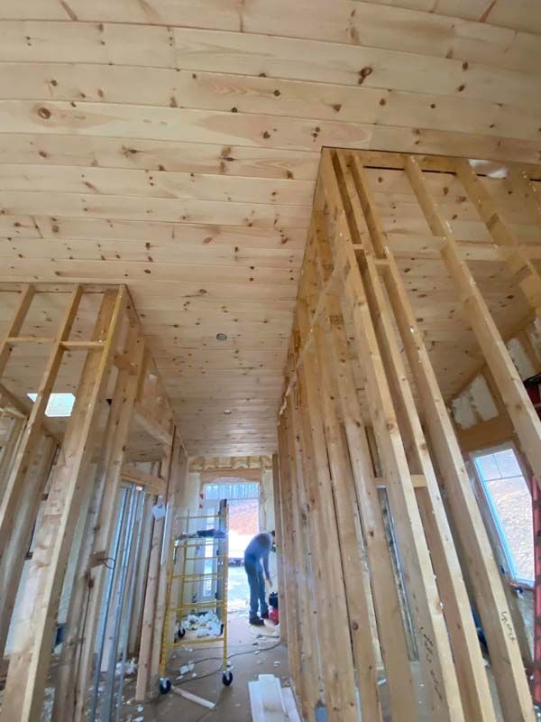 Interior framing of a building with exposed wooden beams, a person working in the distance.