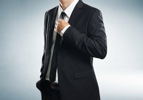 uomo in abito formale che si sistema la cravatta