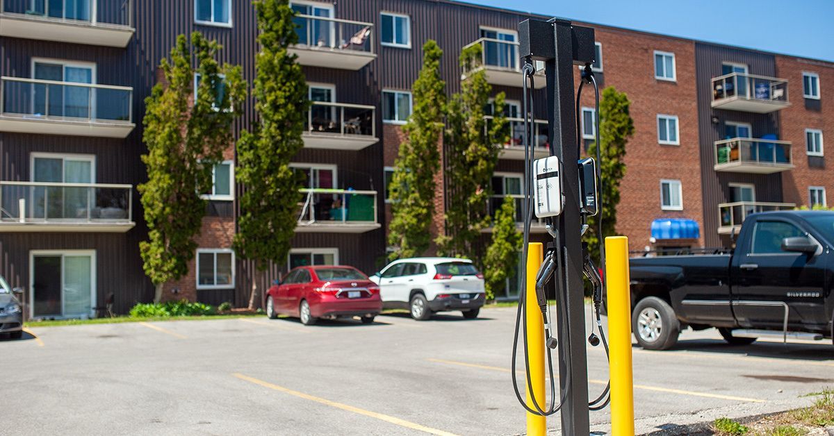 A parking lot at an apartment complex features an electric vehicle charging station in the foreground.