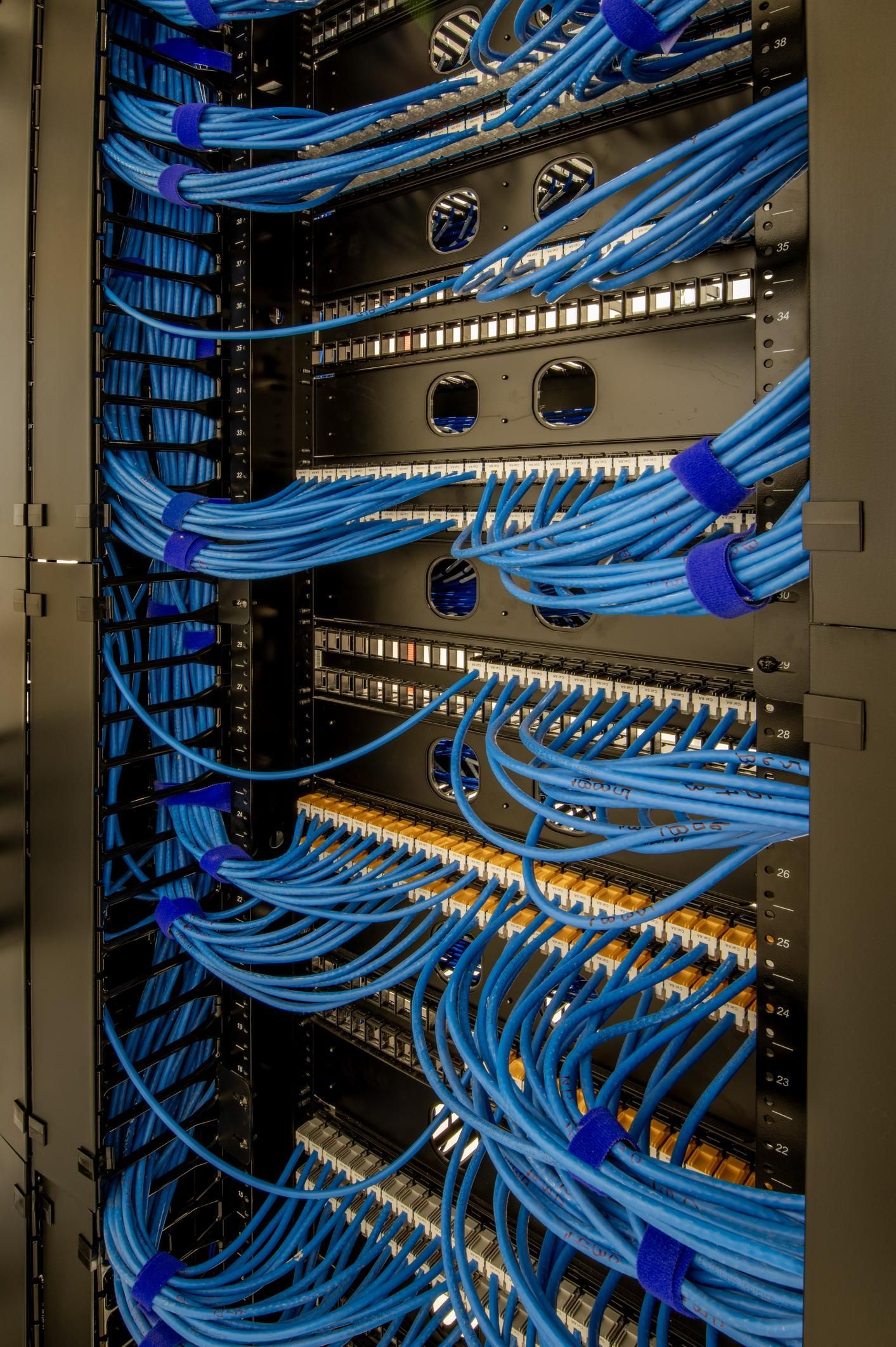 A server rack with neat, blue Ethernet cables organized in bundles and connected to patch panels.